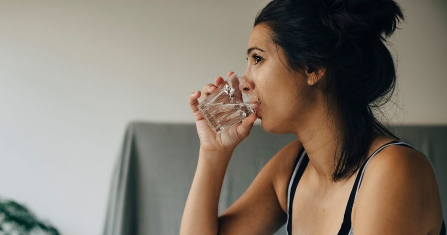Woman taking medicine while sitting on bed at home