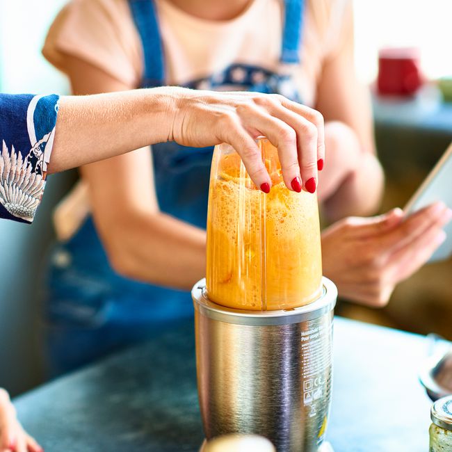 Woman preparing smoothie in blender